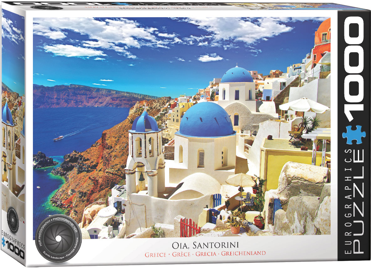 A view of Oia, a small town in Greece, with white-and-blue domed houses arranged along a steep slope and homes carved into the rock.
